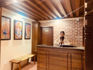 Una donna è in piedi dietro un bancone in una stanza di Harsha Boutique Hotel a Kathmandu