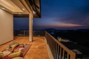 a balcony with a view of the mountains at night at SaffronStays Glasscape in Dehradun