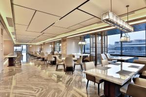 un ristorante con tavoli e sedie e grandi finestre di SSAW Boutique Hotel Yingyang a Hangzhou