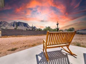 a wooden bench sitting on a sidewalk in front of a sunset at Boulder Apache Junction in Apache Junction