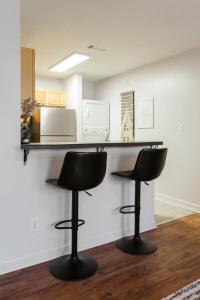 Zwei schwarze Barhocker vor einer Theke mit Mikrowelle in der Unterkunft The Cozy Corner Near Downtown 2Br in Athens + 17 Fotos