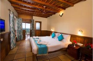 a bedroom with a large white bed with blue pillows at Lazo Golden Valley Resort , Munnar in Munnar +49 photos