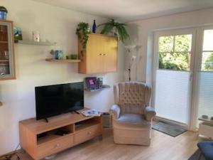 a living room with a flat screen tv and a chair at Ferienwohnung Ingrid in Langballig