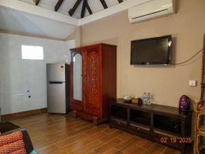 a living room with a refrigerator and a tv on the wall at Neang Aun Kep in Kep