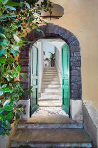 an archway leading up to a staircase with green doors at Il Pozzillo Maison in Massa Lubrense