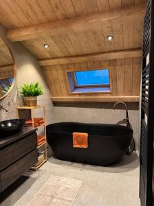 a bathroom with a black tub and a sink at 't Voorhuys Noordwijk aan Zee- tuin en gratis parkeren in Noordwijk