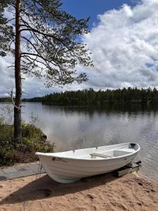 a white boat sitting on the shore of a lake at Riverside cabin Hiekkaranta in Kuusamo