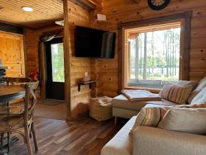 a living room with a couch and a television in a log cabin at Riverside cabin Hiekkaranta in Kuusamo