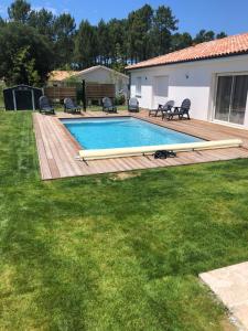 Maison de vacances Moliets et maa في موليات-إي-ما: حديقة خلفية بها مسبح وسطح خشبي