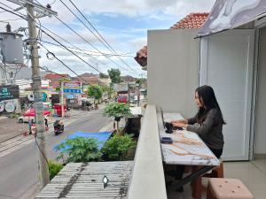 a woman standing at a table on a balcony at Koala Tidur Hostel Syariah Yogyakarta in Seturan