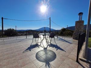 a table and chairs on a patio with the sun at Thelya - Stone House in Apóllona