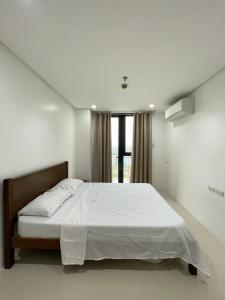 a bedroom with a large white bed with a window at 1 Bedroom Unit at One Pontefino Tower in Batangas City +10 photos