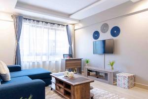 a living room with a blue couch and a tv at Wellivia Suites Serviced Apartments in Nairobi