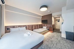 a hotel room with two beds and a television at Apartment Hotel 11 Kuromon 4 in Osaka
