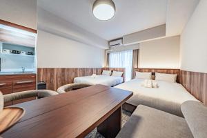 a hotel room with two beds and a table at Apartment Hotel 11 Kuromon 4 in Osaka