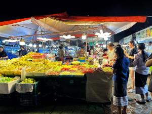 a market with people standing around a fruit stand at DaViKa Hotel in Vientiane