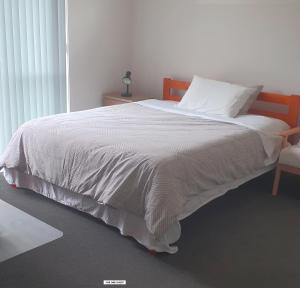 1 cama con edredón blanco y silla en 19 Arahi Place, Rototuna North -Hamilton NZ, en Hamilton