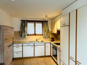 eine kleine Küche mit weißen Schränken und einer Spüle in der Unterkunft Flensa-Ferienwohnung in Seewis im Prättigau