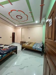 2 letti in una camera con un dipinto sul soffitto di Chandrika palace 500 meter from ayodhya railway and ram mandir a Ayodhya