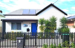 a white house with a fence and a blue door at Eleda House Hunter Valley in Cessnock