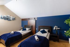 two beds in a room with blue walls at Beskid Apartment 11 z widokiem na góry, Sauna, Jacuzzi in Szczyrk