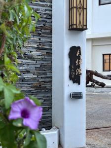 a sign on the side of a building with a purple flower at 月伴灣海景民宿MoonBay Seaview Homestay - 半自動入住 Self check-in in Binlang