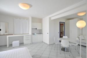 a white kitchen with a table and white chairs at Villa Grachira in Fertilia