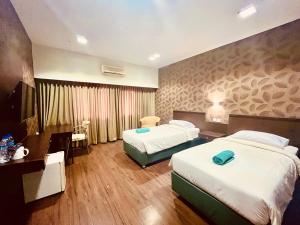 une chambre d'hôtel avec deux lits et un bureau dans l'établissement City Hotel Balikpapan, à Klandasan-besar