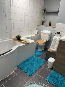 a bathroom with a tub and a toilet and two rugs at Luxe city stay in Ipswich