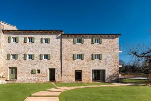 a large brick building with a grass yard in front at Villa Paladnjaki - breakfast included in Žminj