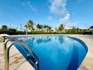 ein blauer Pool mit Palmen im Hintergrund in der Unterkunft Flat Aquaville perto do Beachpark com 3 Suites in Aquiraz