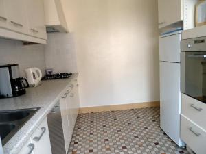 una pequeña cocina con electrodomésticos blancos y suelo de baldosa. en Les Chenets, en Chambon-sur-Lac