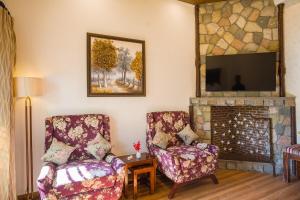 a living room with two chairs and a fireplace at 3-BHK Retreat with Picturesque Balcony & Patio in Rājpur +27 photos