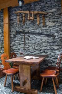 a wooden table with a glass of wine and two chairs at Hotel Chez Toi in Oulx