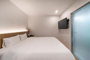 a bedroom with a large white bed and a tv at Busan Gwangan Holic Story Hotel in Busan
