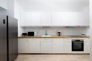 a kitchen with white cabinets and a stainless steel refrigerator at First Estates Apartment 2BR in Voluntari