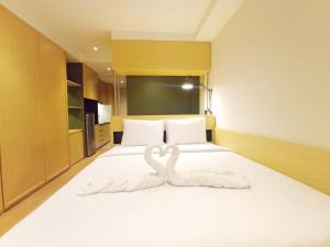 a bedroom with two swans made out of towels on a bed at Comfy and Best Deal Studio at Mataram City Apartment By Travelio in Kejayan