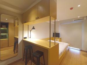 a room with a desk with stools and a bed at Comfy and Best Deal Studio at Mataram City Apartment By Travelio in Kejayan