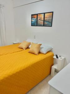 une chambre avec un lit jaune avec deux oreillers dans l'établissement Apto Edif viva a vida, à Bertioga