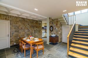 a dining room with a table and a staircase at StayVista at Villa Vienna with Lawn & Bonfire in Mukteswar