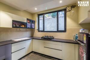 a kitchen with white cabinets and a window at StayVista at Villa Vienna with Lawn & Bonfire in Mukteswar +22 photos