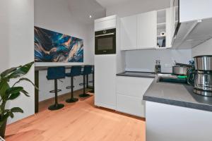 een keuken met witte kasten en een aanrecht met krukken bij Exclusive Bungalow! 4 rooms, 8 people, 2x parking in Dresden