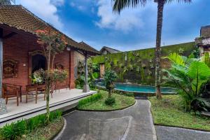 a garden with a swimming pool and a house at The Alus Villa and Suite in Ubud