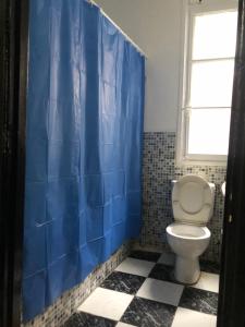 a bathroom with a toilet and a blue shower curtain at Maison de la paix in Casablanca