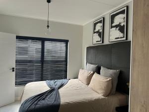 a bedroom with a bed with a black headboard and a window at 745@TheBlyde in Pretoria