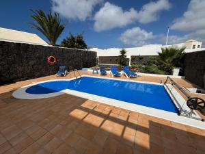 basen z krzesłami obok budynku w obiekcie Villa Adel 56, private heated pool, parking w mieście Playa Blanca