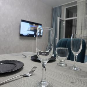 zwei leere Weingläser auf einem Tisch mit einem TV in der Unterkunft ЖК Панорама Парк in Qostanai