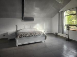 une chambre blanche avec un lit et une fenêtre dans l'établissement Villa Cotopaxi, Cerro Azul, à Los Altos de Cerro Azul
