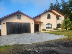 une grande maison blanche avec un garage dans l'établissement Villa Cotopaxi, Cerro Azul, à Los Altos de Cerro Azul