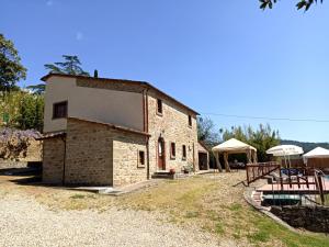 Un antiguo edificio de piedra con una mesa y sombrillas. en Agriturismo Poggiolo, en Castiglion Fiorentino